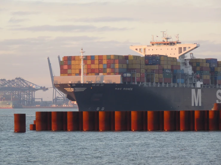 a cargo ship passing through the harbor with large orange posts