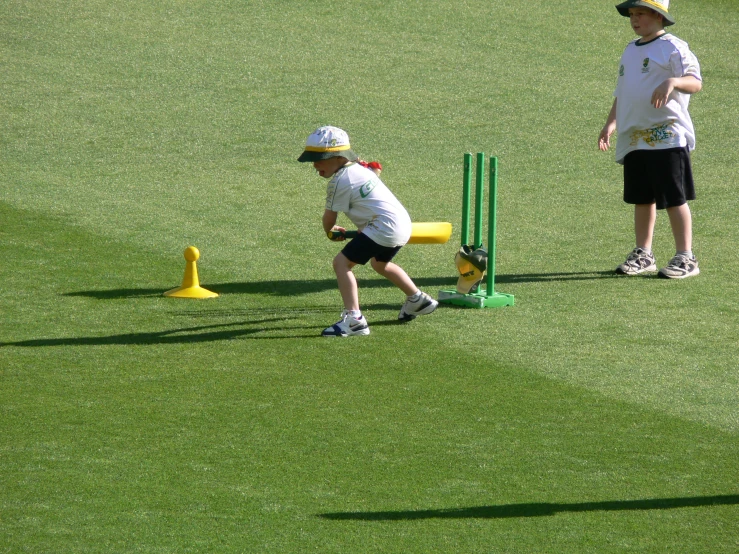 two boys playing a game of cricket on a field