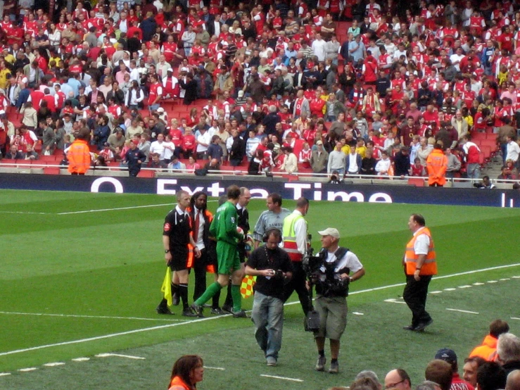 an umpire stands next to two men on a soccer field