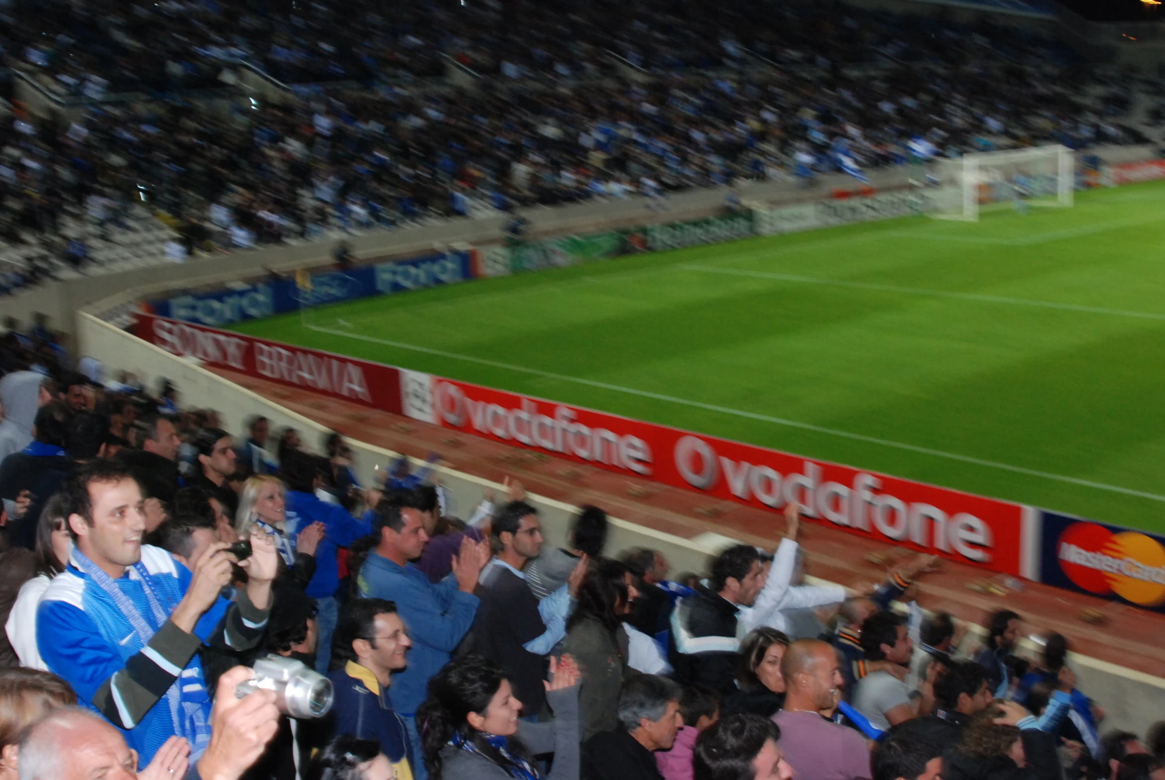 the crowd is standing in front of a soccer field with people at it