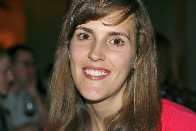 a woman wearing a pink top smiling and looking off to her left