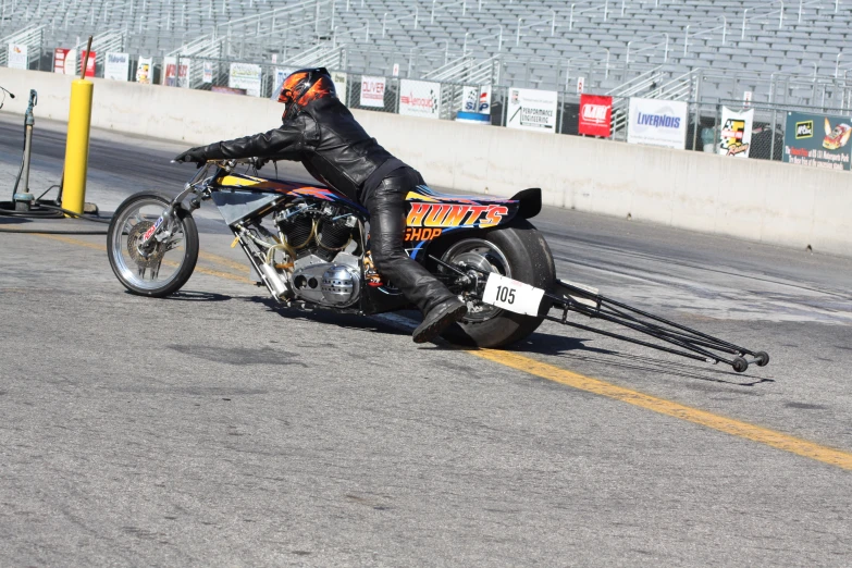 a man wearing leather and standing over a motorcycle tire