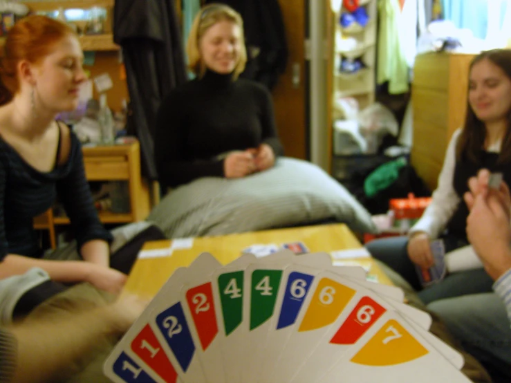 several women sitting around playing cards in the same room
