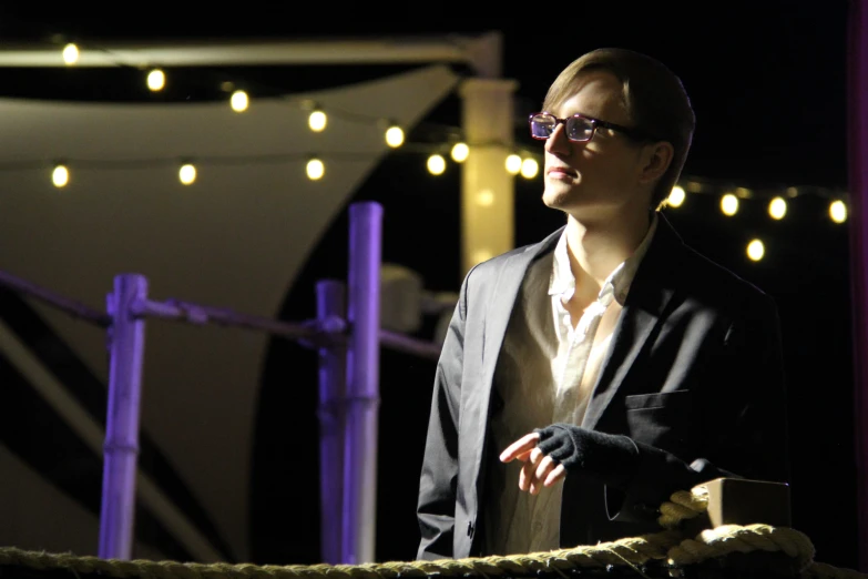 a man wearing glasses standing next to a rope