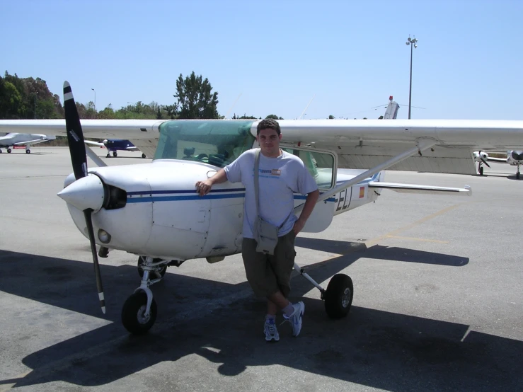 a man is posing by a small plane