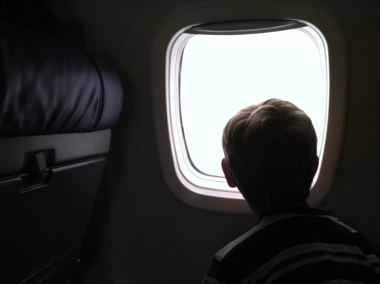 boy staring at window during flight in an airplane