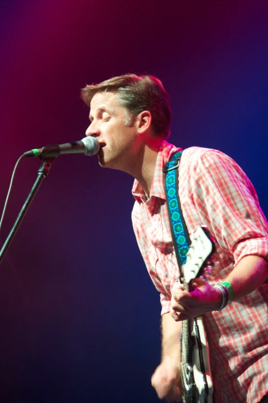 a man is singing into a microphone at a concert