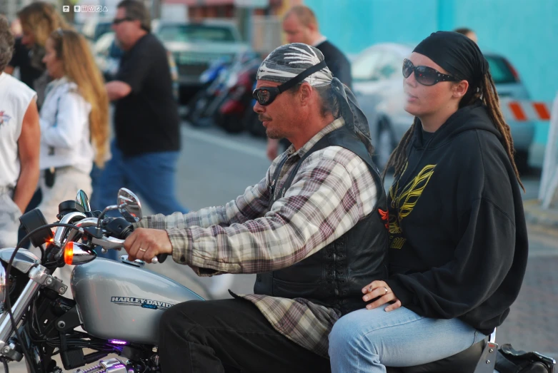 a man and woman riding a motorcycle down a street