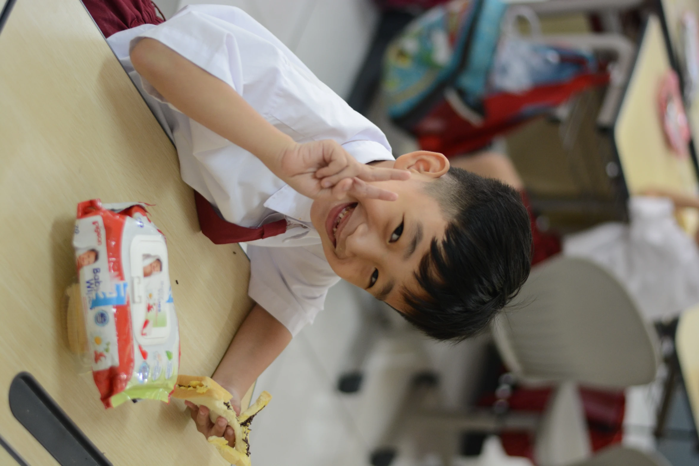 the child is sitting at his desk smiling for the camera