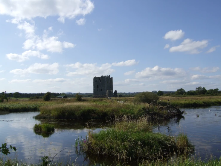 a large water mill on the shore of a pond