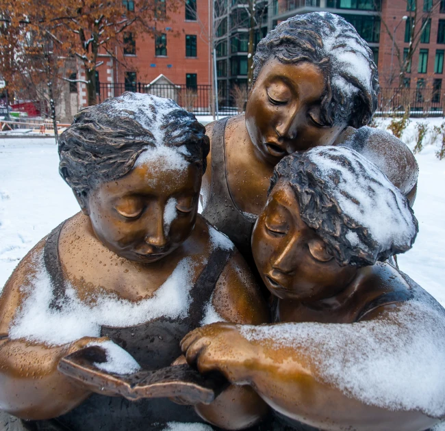 three statues of children are seen next to each other in the snow