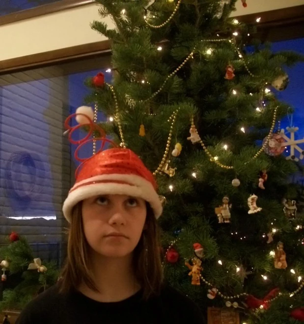 a girl standing by a decorated christmas tree