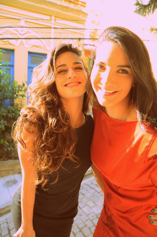 two young women pose for a picture in front of a house