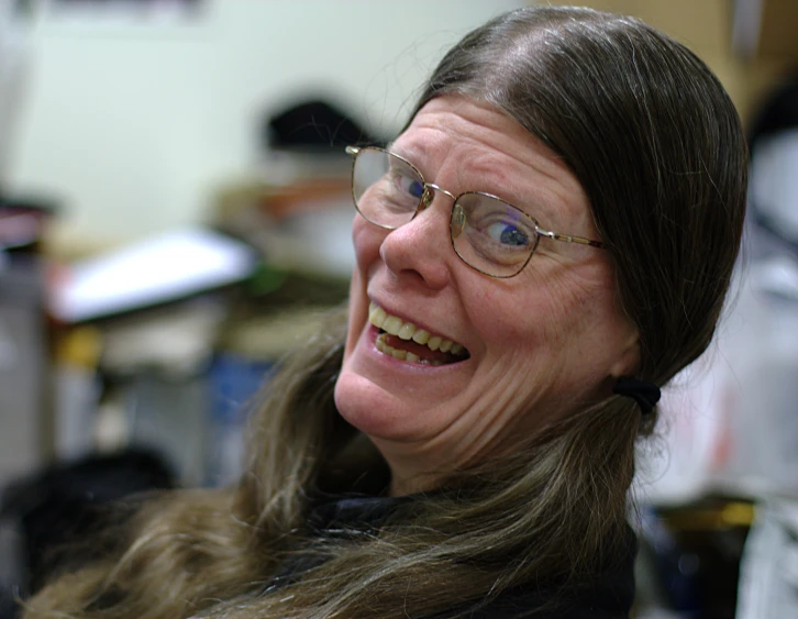 a smiling older woman with long brown hair and glasses