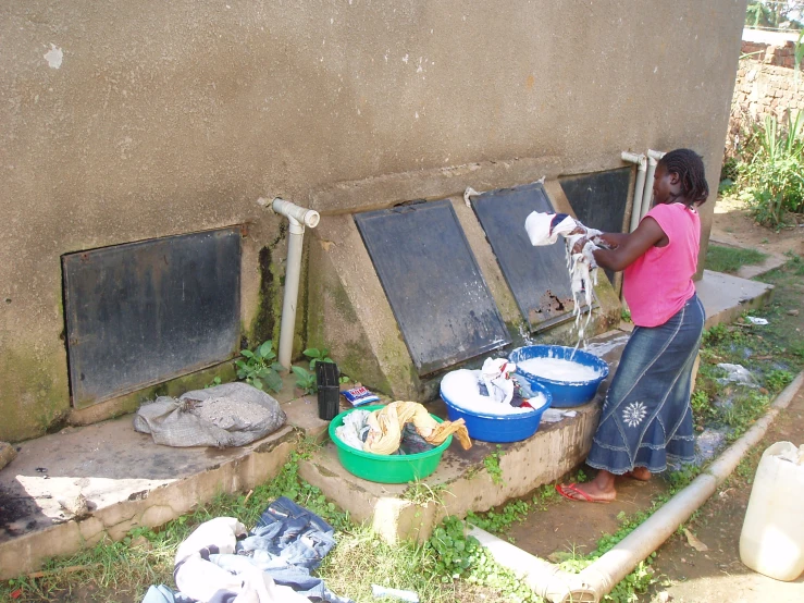 a woman washes dishes outside with a hose