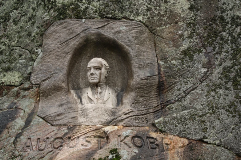 an old stone bust of a man surrounded by moss