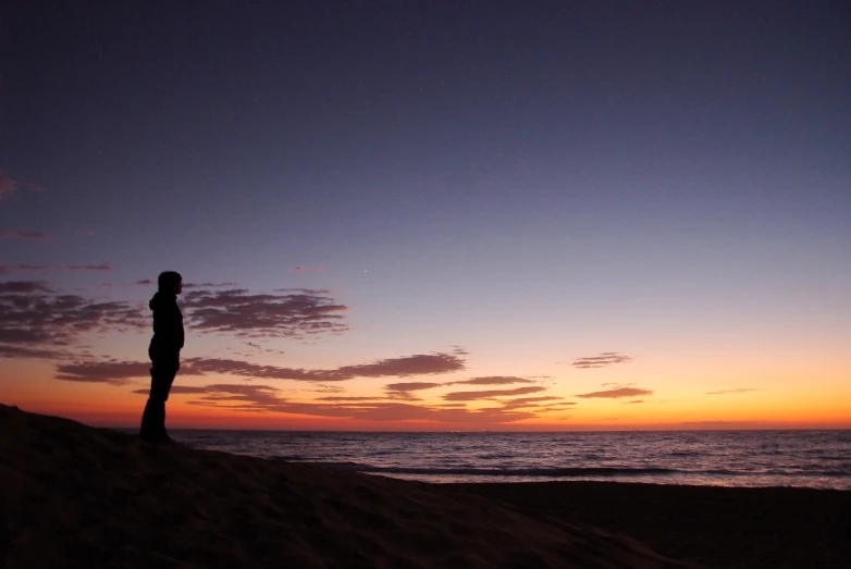 there is a man standing in the sand on a beach