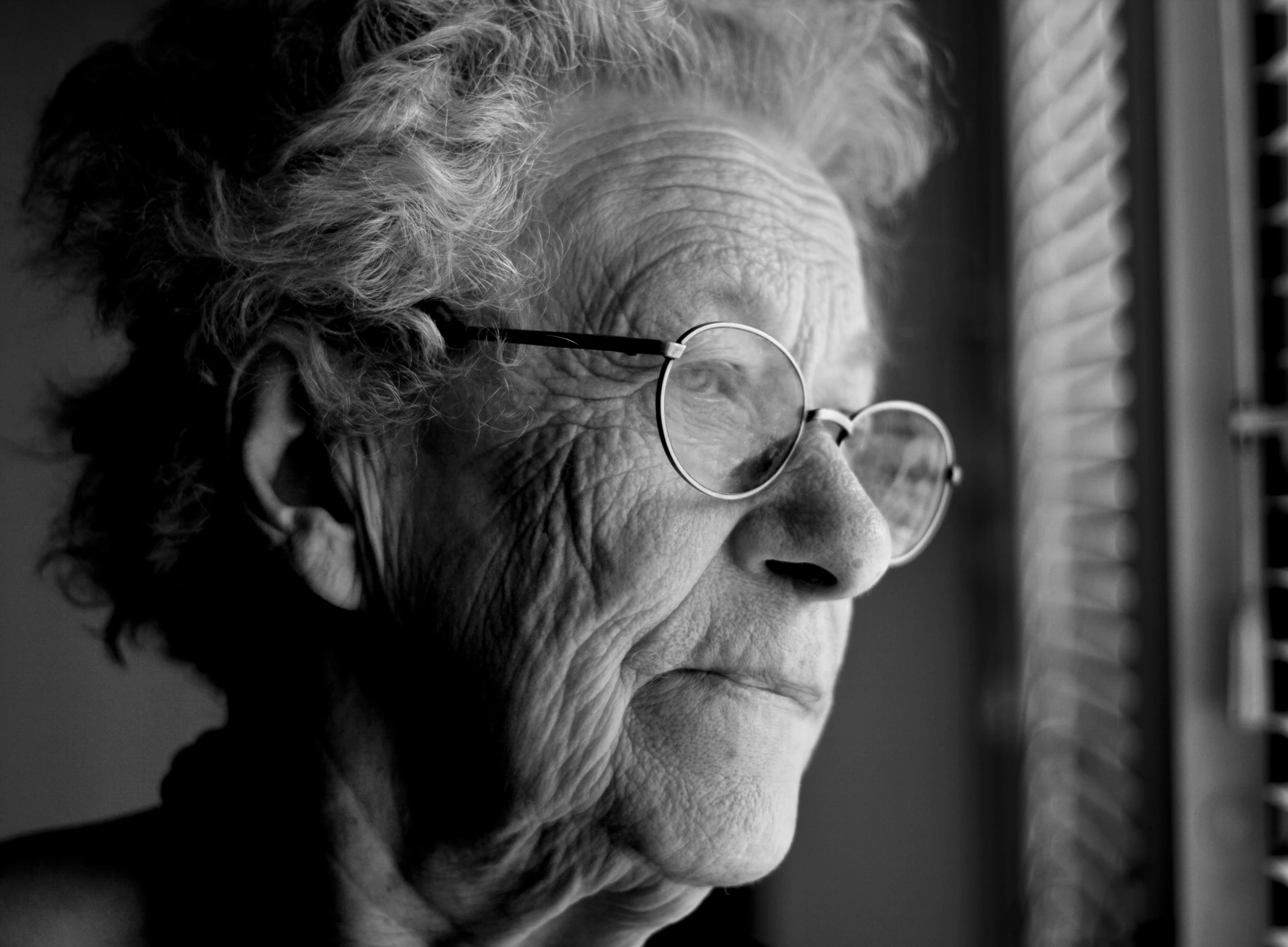 black and white po of an old woman looking out the window