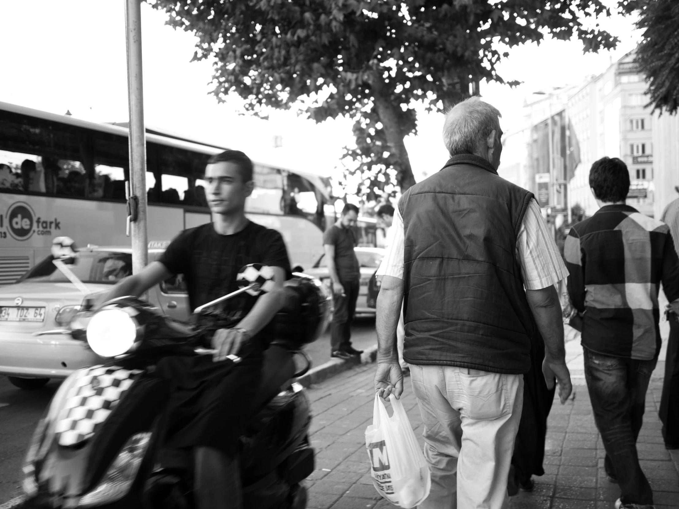 a person on a scooter and two men walking behind them