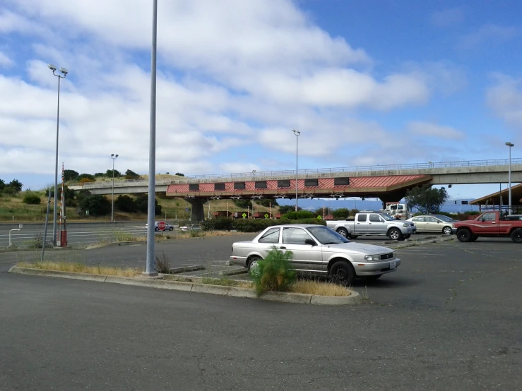 two white cars in parking lot under an overpass