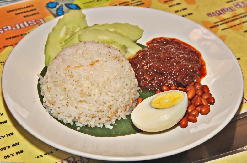 a white plate topped with rice and eggs on a leafy green dish