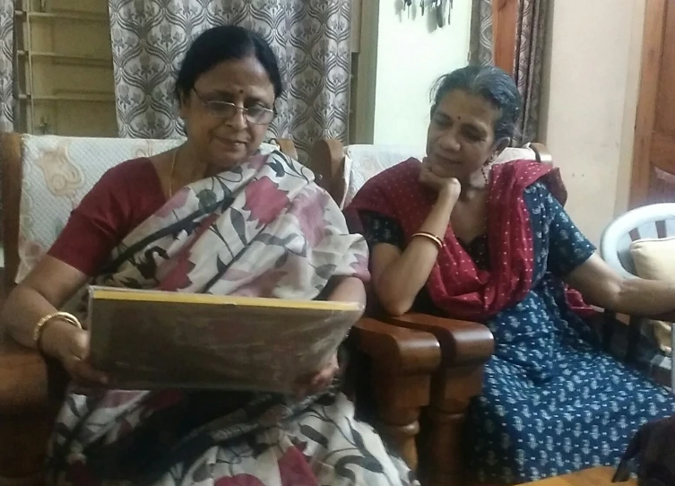 two women sitting on the couch with one looking at the camera