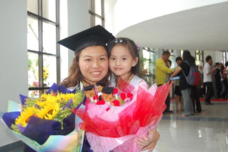 a girl with a flower bouquet holding a woman's graduation cap