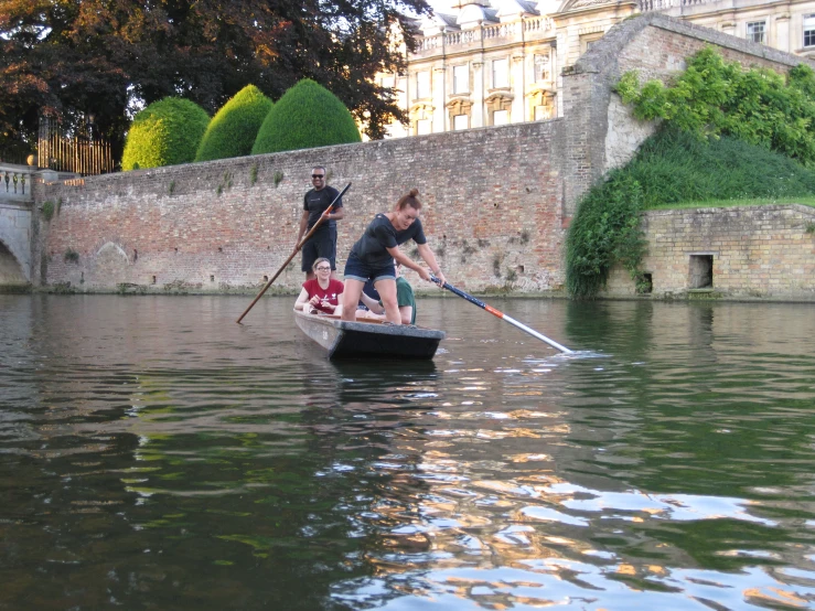 a man and woman paddle a small boat while holding onto another person