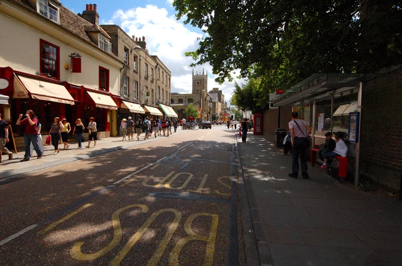 the sun is shining on a city street with people