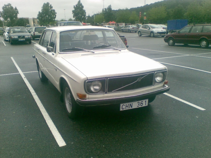 a beige car sits parked in a parking lot