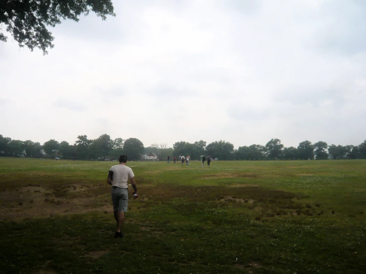 people stand in the distance walking towards a grassy field