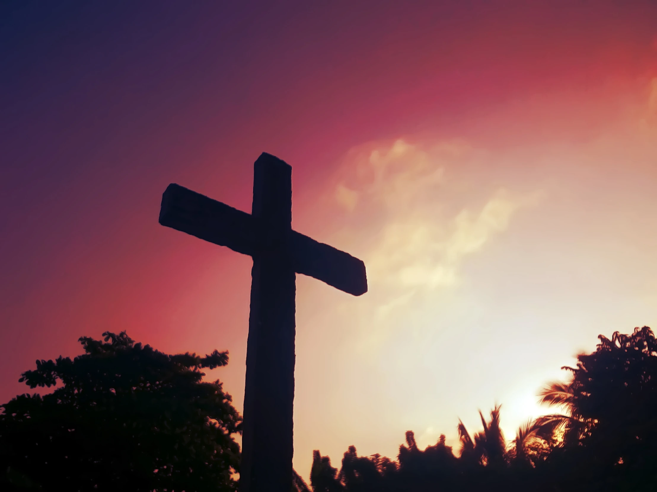 a cross is seen against the sky with trees around