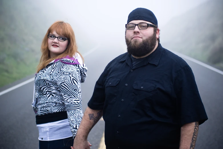 a man and woman standing on a road on the foggy day