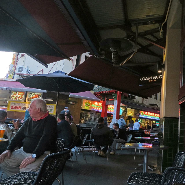 a man sitting under an umbrella outside at a restaurant