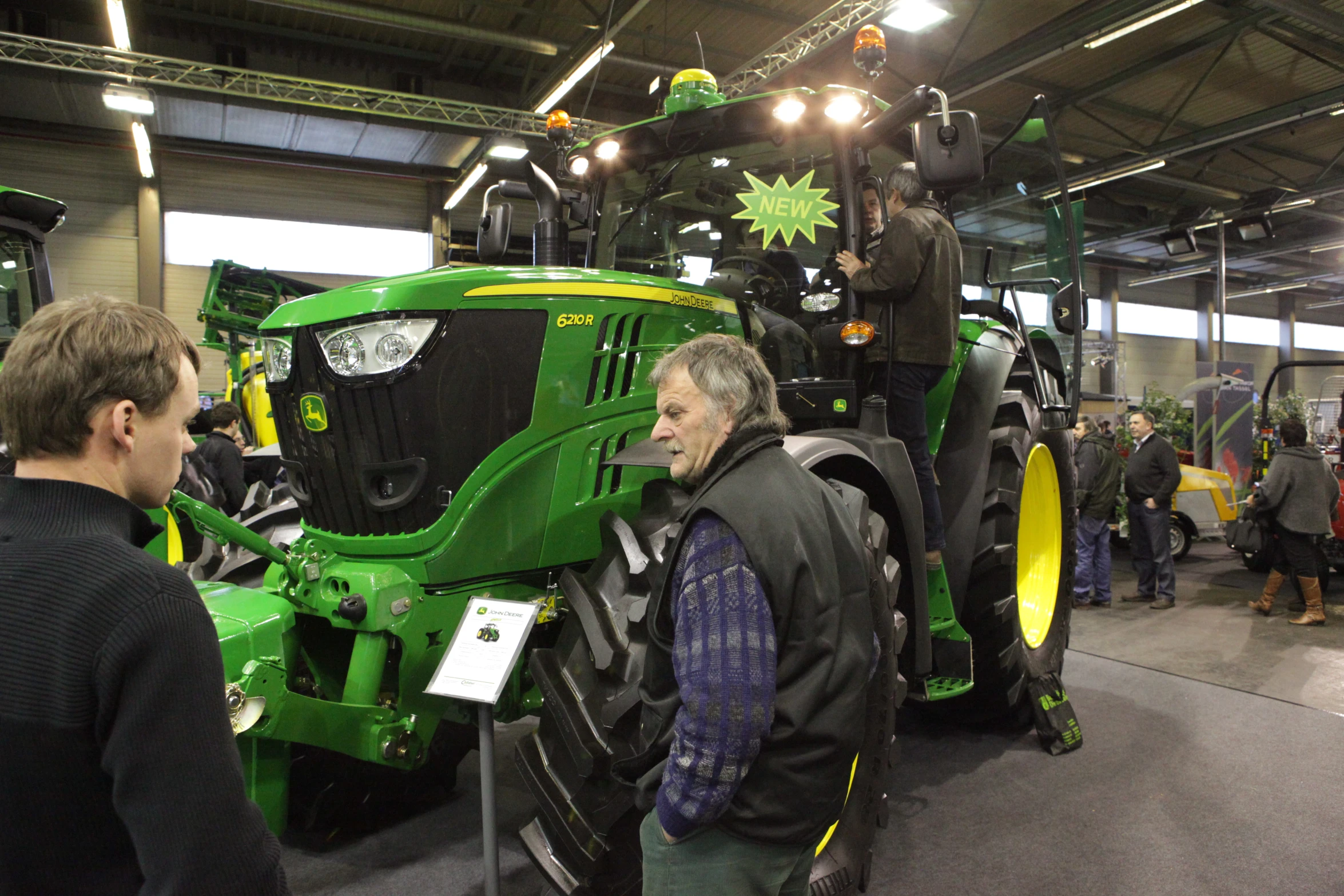 a man standing next to a green tractor inside of a warehouse