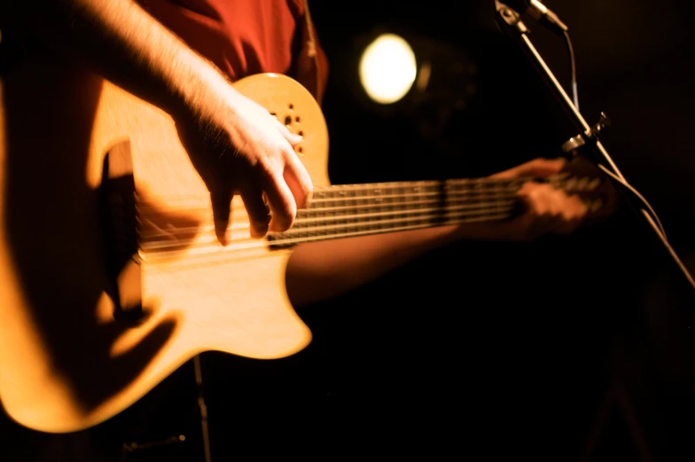 a person holding a guitar and playing on the stage