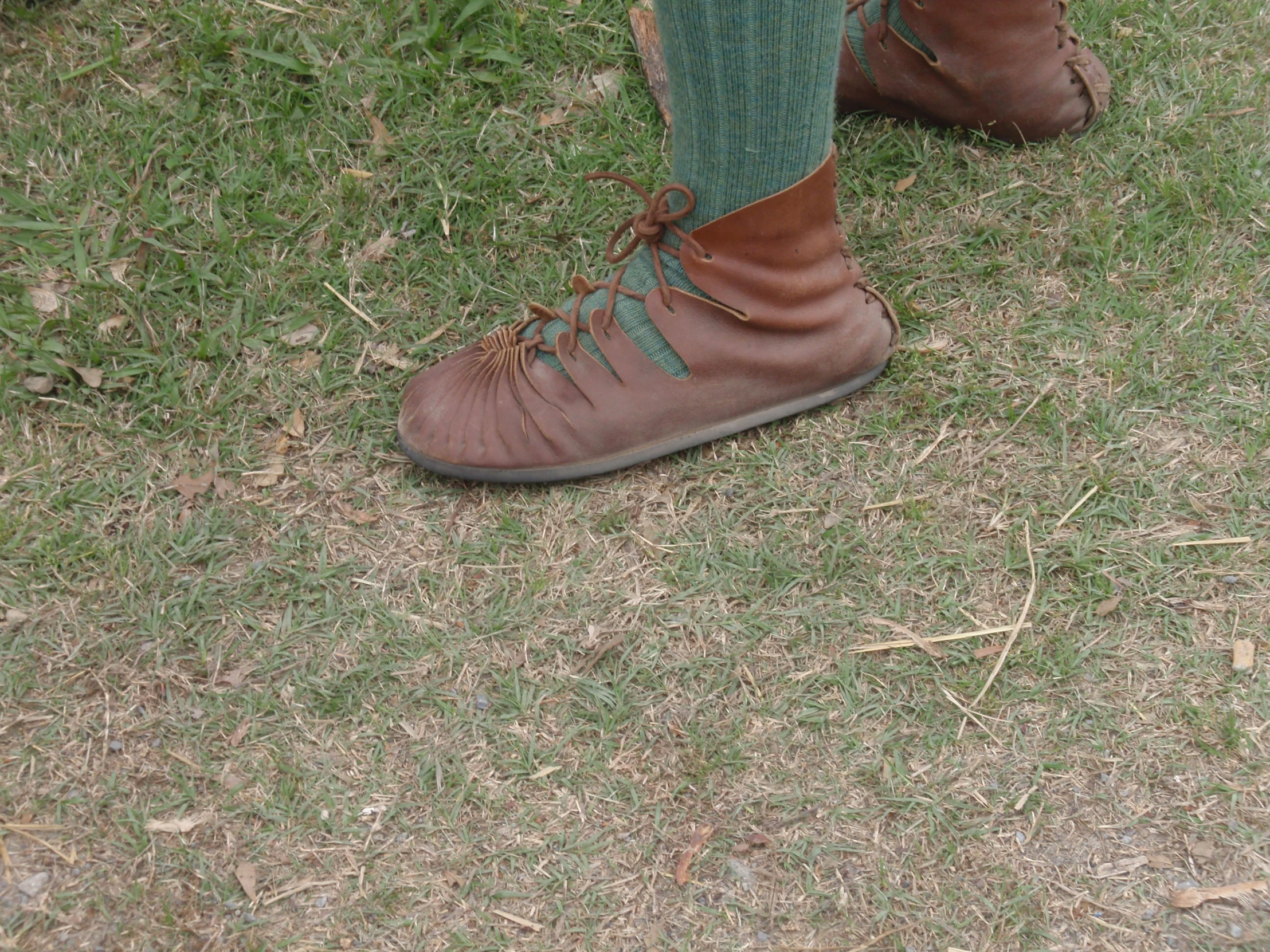 brown shoes are worn by someone standing on the grass