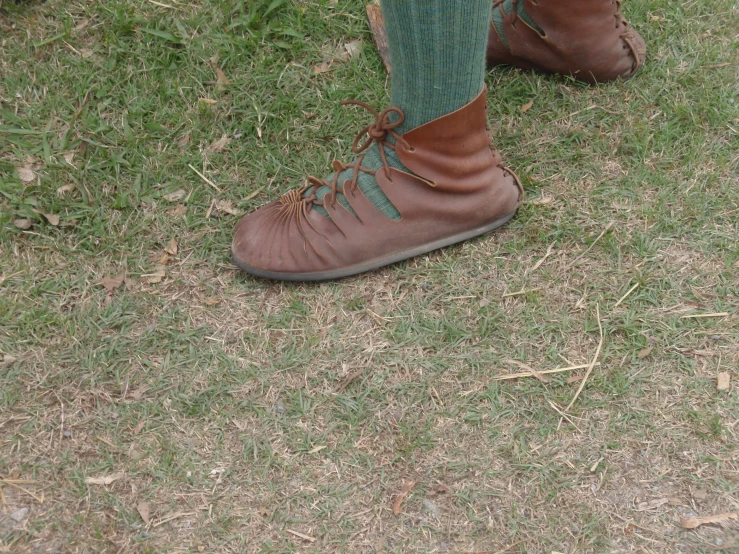 brown shoes are worn by someone standing on the grass