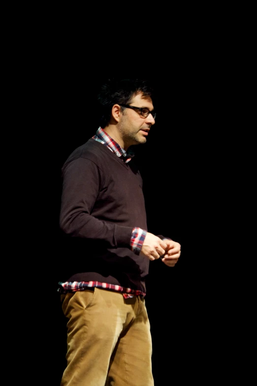 a man in glasses, a red shirt and khaki pants standing up