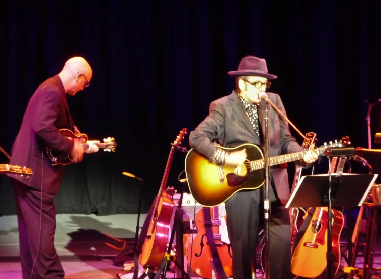 two men are performing on stage playing guitar and accordions