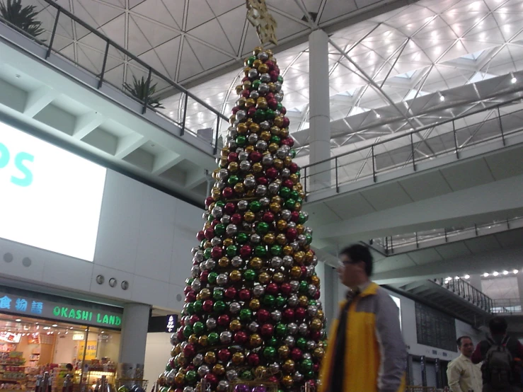 a man walking past a very colorful christmas tree