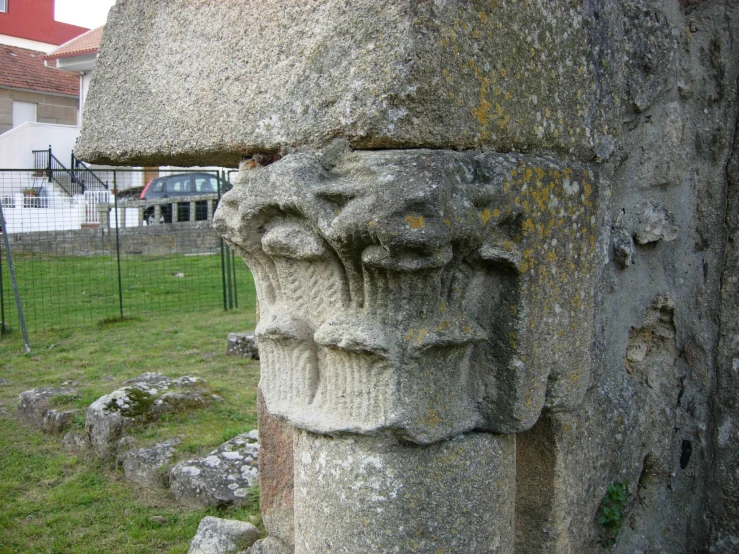 two heads carved into the side of a stone pillar