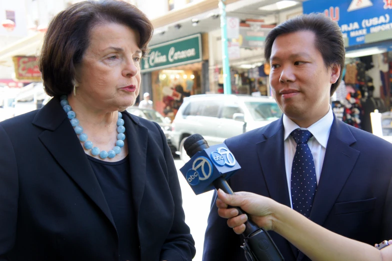 two people in suits and beads standing on the sidewalk