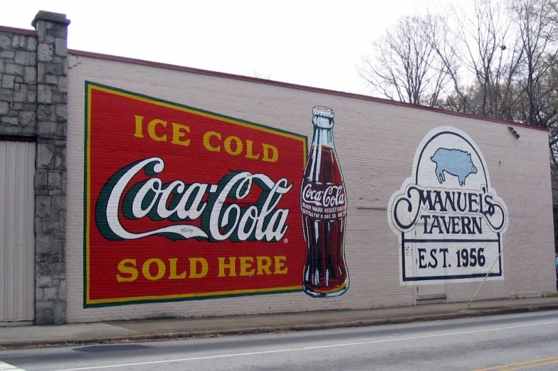 coca - cola advertising on the side of a building with two similar signs