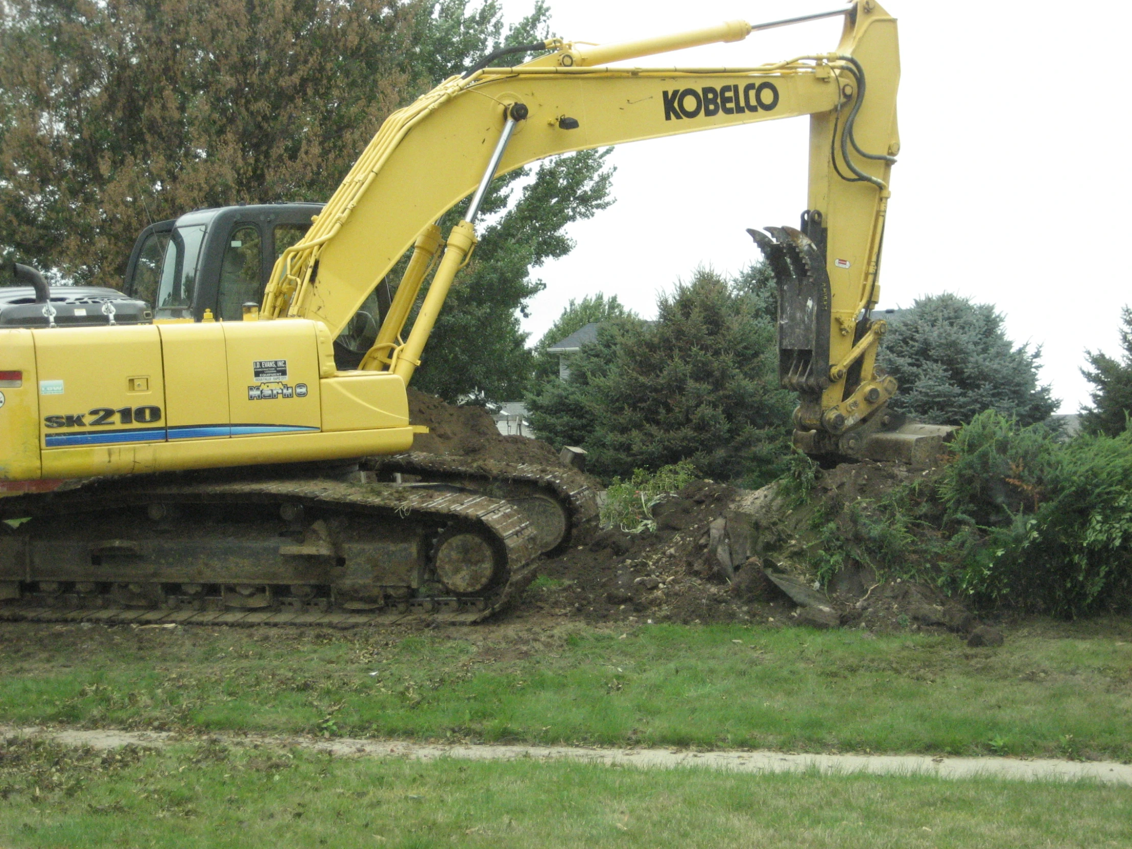 a yellow and black bulldozer is next to some green trees