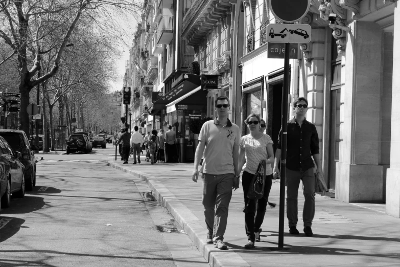 two people walk down a city street while the other is riding a skateboard