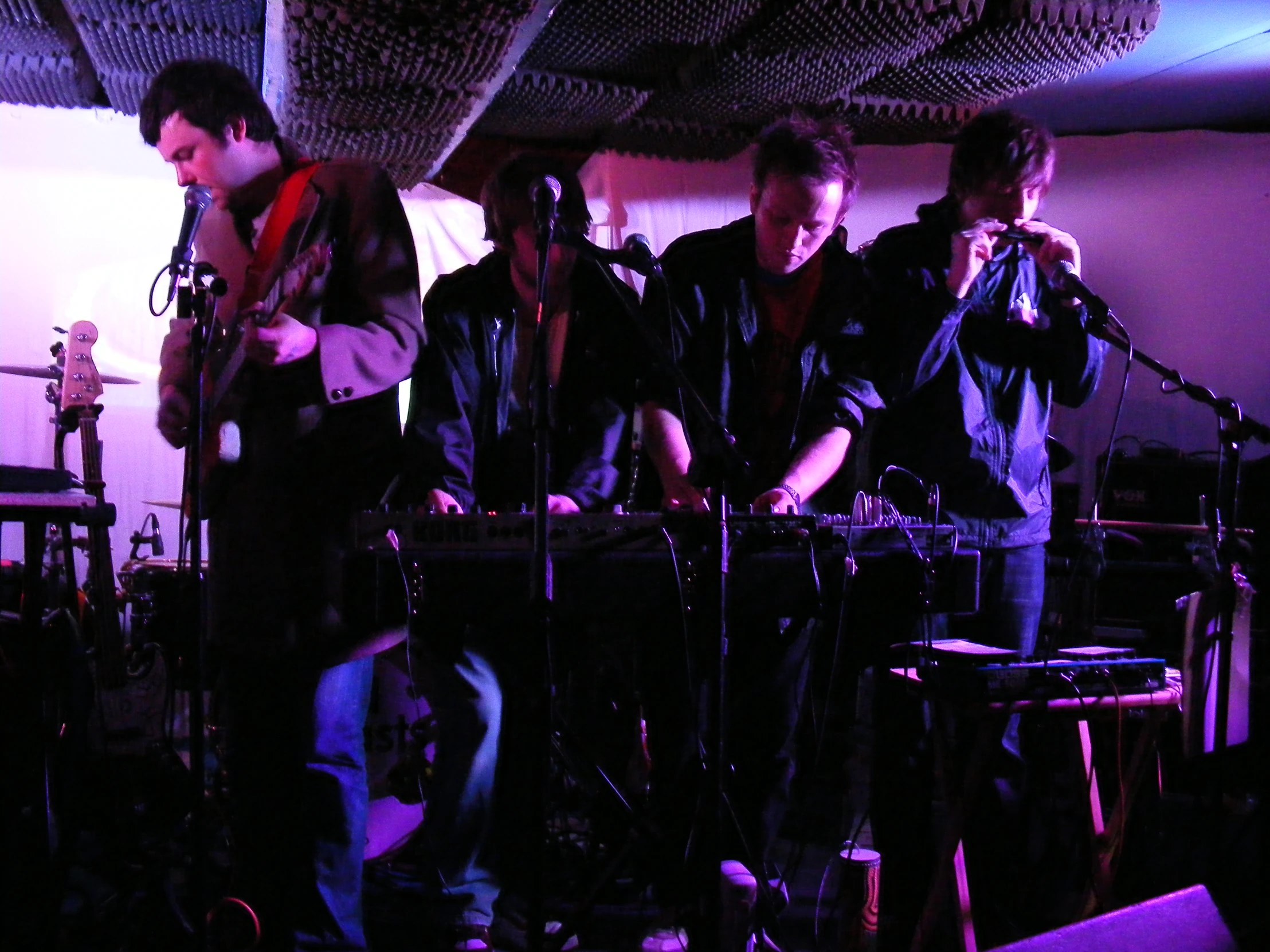 group of men singing into microphones under roof