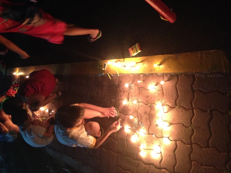 people looking down at some candles on the ground