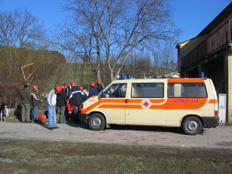 a small van and a group of people standing outside a building