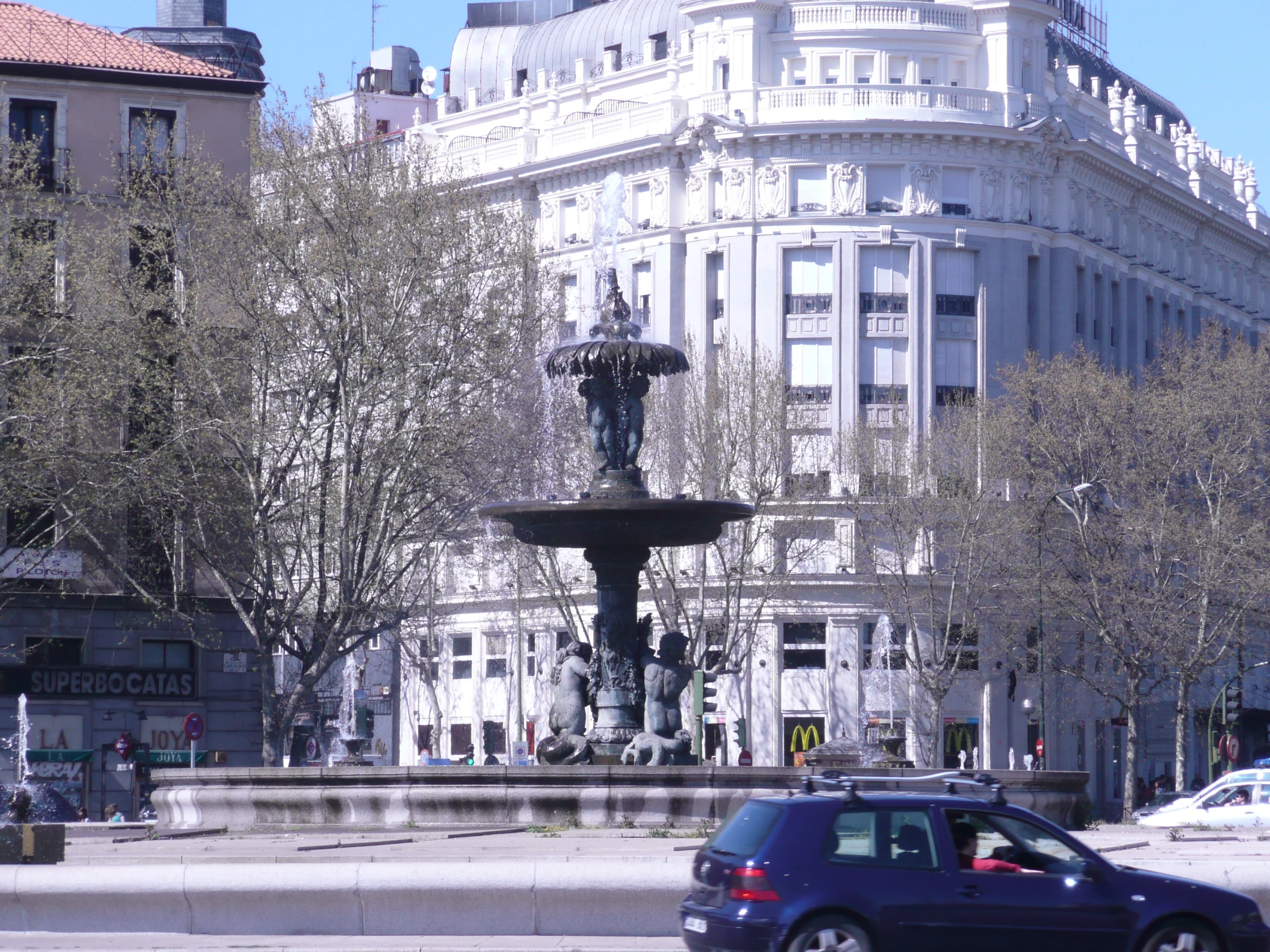 cars are parked in front of a water fountain